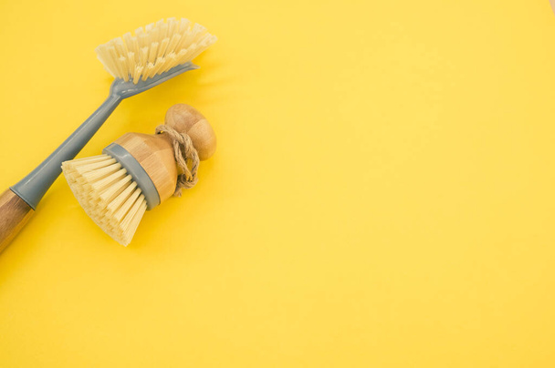 A closeup of a set of wooden dishwashing brushes on a yellow surface - space for text - Valokuva, kuva