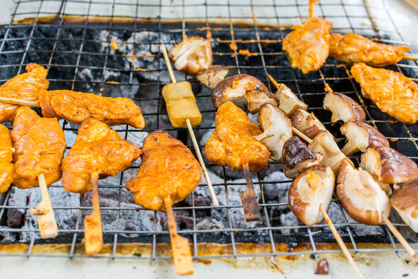 Asorted grilled meats and food over the coals with fire on a barbecue - Photo, Image
