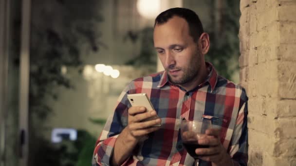 Man drinking wine and texting on smartphone - Кадры, видео