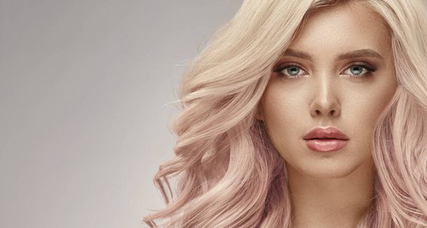 Gorgeous woman with beautiful wavy pink hair on a beige background - Fotó, kép