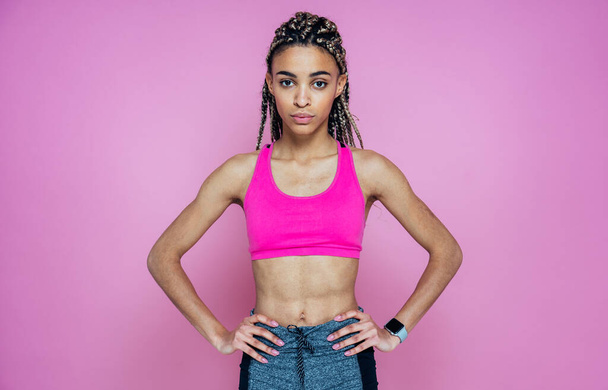 Beautiful girl doing exercises and sport. Posing on a pink colored background - Фото, изображение
