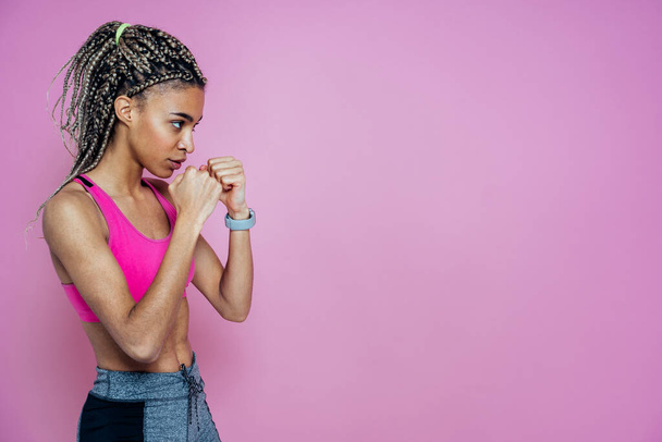 Beautiful girl doing exercises and sport. Posing on a pink colored background - Foto, afbeelding