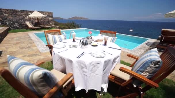 Śniadanie na prywatnym basenie. Ekskluzywny luksusowy ośrodek ze wspaniałym widokiem na morze z idyllicznej greckiej wyspy, Pull Up Aerial - Materiał filmowy, wideo