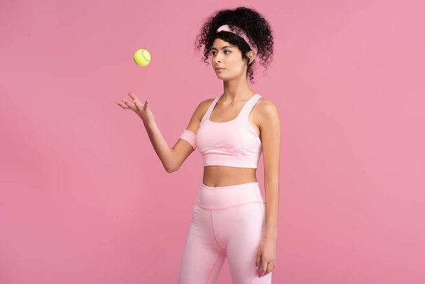 young sportive woman throwing tennis ball in air isolated on pink  - Foto, Bild