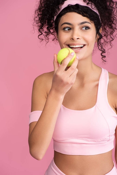 joyful young woman holding tennis ball isolated on pink - Photo, image