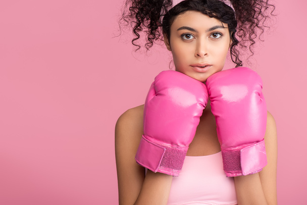 mladá sportovkyně ve sportovním oblečení a boxerských rukavicích při pohledu na kameru izolované na růžové  - Fotografie, Obrázek