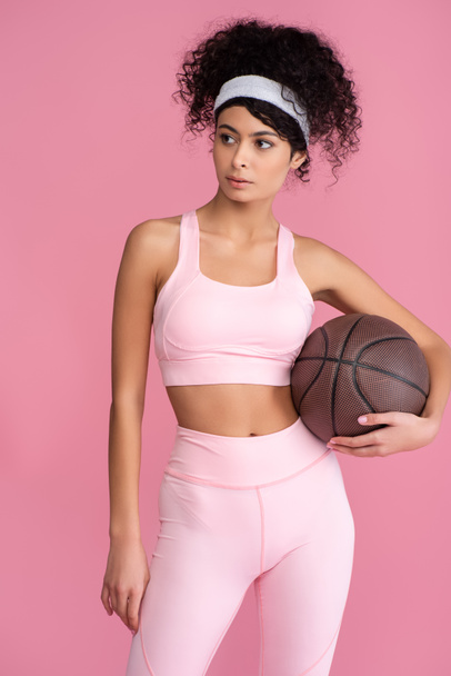 curly young woman holding basketball isolated on pink  - Foto, Imagen