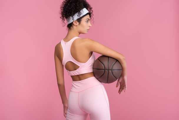 jeune femme bouclée tenant basket et regardant loin isolé sur rose  - Photo, image