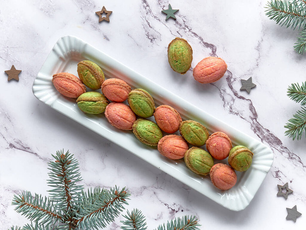 Walnut shaped Cookies with Dulce De Leche. Tasty creative dessert in green and red on marble table with winter decorations, fir twigs, and plywood stars. - Valokuva, kuva