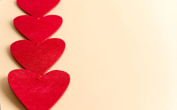 Rote Herzen in Nahaufnahme liegen auf beigem Hintergrund, valentinisches Hintergrundkonzept mit Kopierraum und flacher Lage - Foto, Bild