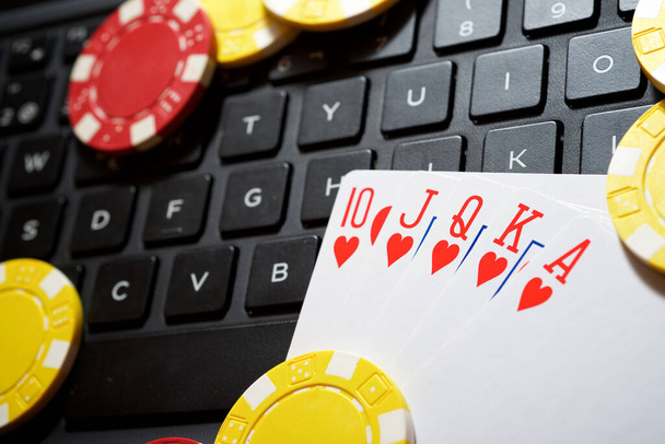 Casino chips en kaarten stapelen op een laptop. - Foto, afbeelding