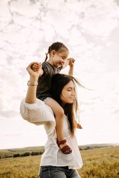 красивая счастливая мать и ребенок, проводящие время вместе на природе - Фото, изображение