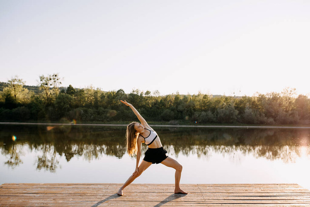 beautiful young woman practicing yoga outdoors - 写真・画像