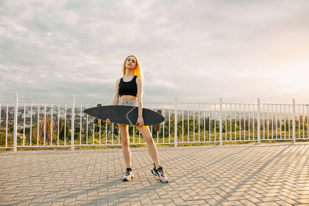 beautiful young woman with long board on street - Foto, Imagen