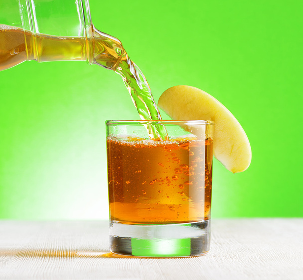 Apple juice pouring from jug into a glass - Fotografie, Obrázek