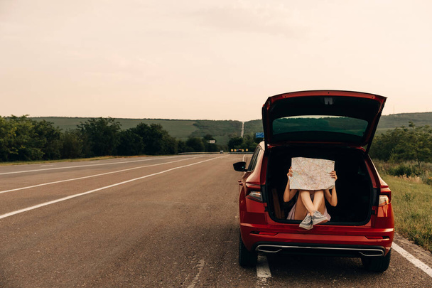 femme avec carte assis dans le coffre de voiture ayant voyage en voiture pendant les vacances d'été - Photo, image