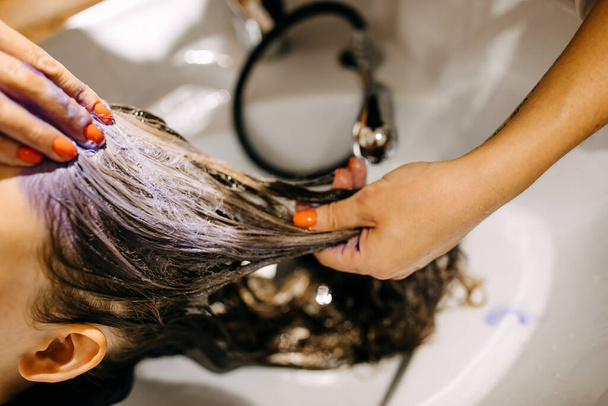 парикмахер рисует волосы женщины в салоне - Фото, изображение