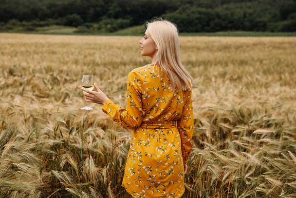 красивая молодая блондинка в желтом платье с соломенной шляпой расслабляющей на природе - Фото, изображение