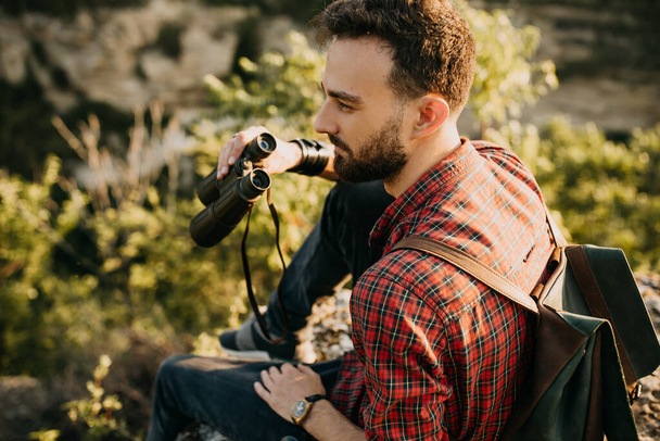 portrait of handsome young man with binoculars on nature - Photo, Image