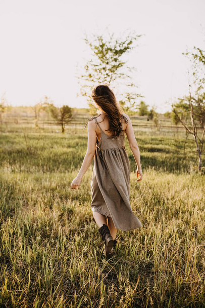 attractive young woman in dress on nature during sunset - Фото, изображение