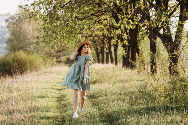 kaunis nuori nainen mekko ja olki hattu omena puutarhassa auringonlaskussa - Valokuva, kuva