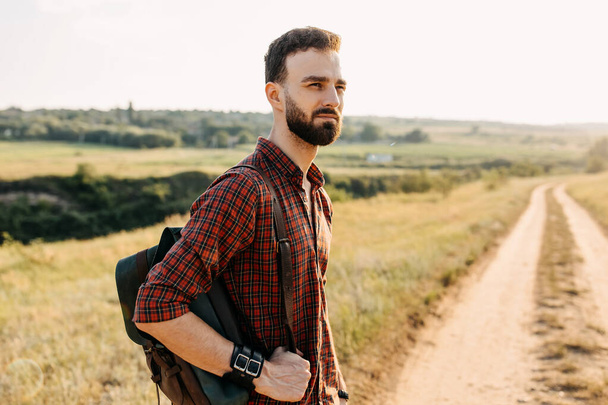 portrait of handsome young man with leather backpack on nature - Photo, Image
