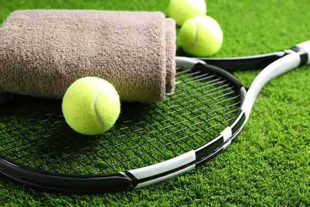 Tennis racket, towel and balls on green grass, closeup. Sports equipment - Foto, Imagen