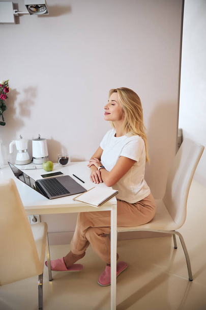 Charming blonde Caucasian business woman spending time at the modern laptop in the indoors - Foto, imagen