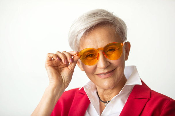 beautiful stylish woman aged in a red jacket in sunglasses - Photo, Image