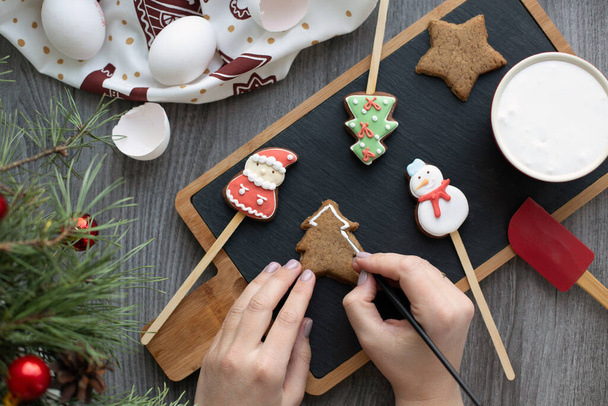 Pose plate avec pain d'épice de Noël traditionnel. Processus de décoration avec des mains féminines. Nouvelles couleurs année - Photo, image