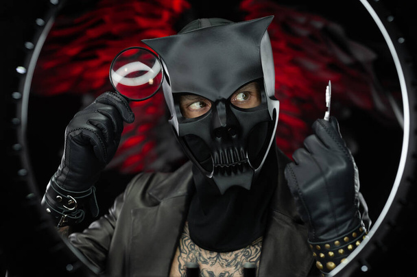 el hombre que lleva una máscara de cráneo de demonio en una capa de cuero con una lupa y pastillas - doctor malvado - Foto, imagen