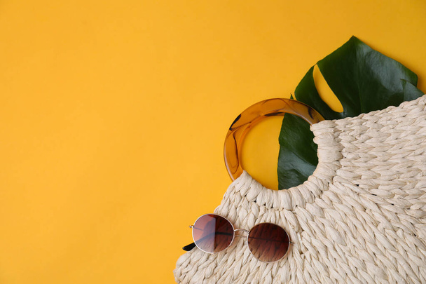 Stylish straw bag and sunglasses on yellow background, flat lay with space for text. Summer accessories - Φωτογραφία, εικόνα