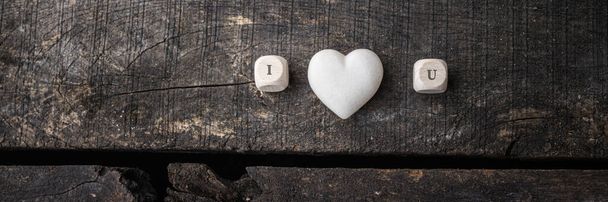 Miluju, když se na dřevěném dlaždici píše nápis s mramorovým srdcem uprostřed. Přes rustikální dřevěné pozadí. - Fotografie, Obrázek