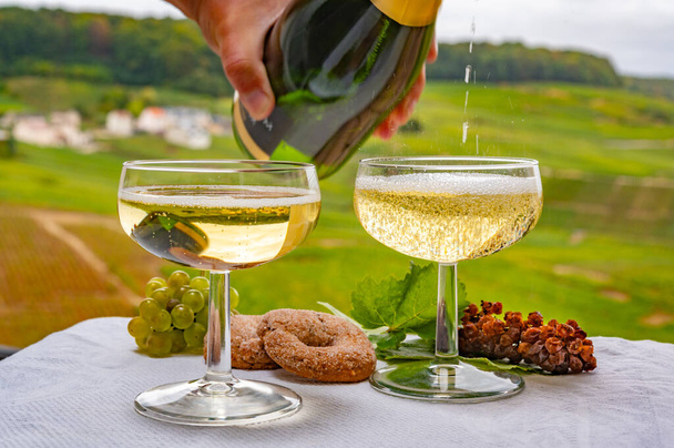 Ochutnávka francouzského šumivého bílého vína s bublinkami šampaňského na venkovní terase s výhledem na zelené vinice Grand Cru Champagne v Cramantu, poblíž Epernay, Francie - Fotografie, Obrázek