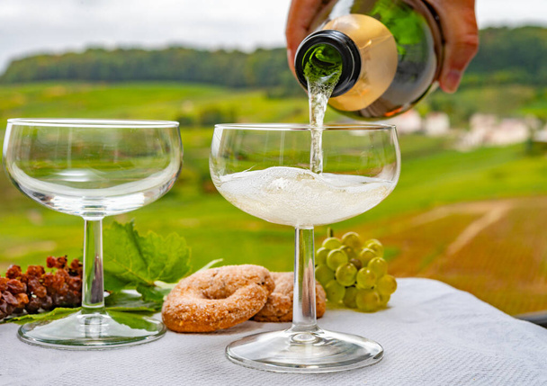 Tasting of french sparkling white wine with bubbles champagne on outdoor terrace with view on green grand cru Champagne vineyards in Cramant, near Epernay, France - Photo, Image