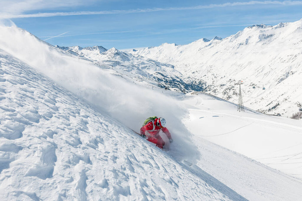 Imagen en stock de un esquiador freeride que está esquiando cuesta abajo en nieve en polvo profundo. Grandes montañas y cielo azul en el fondo. La ubicación es Hochgurgl y Obergurgl en Austria - Foto, Imagen