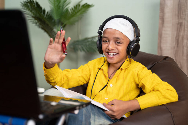 Мусульманский ребенок занят в онлайн классе, делая видеозвонок на ноутбуке - концепция новой нормальной, электронного обучения, виртуального образования и домашнего обучения из-за коронавируса или ковид-19 пандемии - Фото, изображение