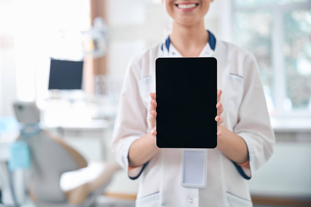 Dentista feminina sorridente com tablet no escritório - Foto, Imagem