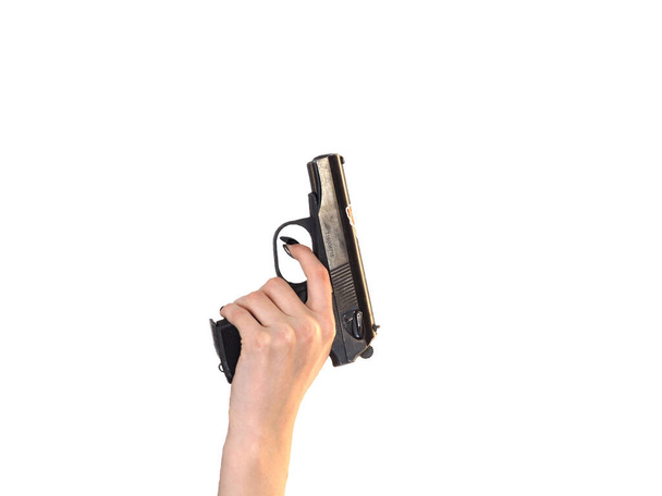 De hand van een vrouw met een pistool op een witte geïsoleerde achtergrond. Meisje met een pistool, studiofoto. Het begrip feminisme, gelijkheid. - Foto, afbeelding
