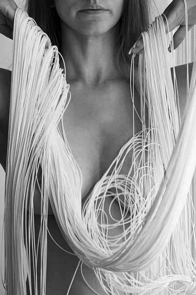 Corpo nu sexy atraente, queixo e boca de uma jovem mulher linda, parcialmente obscurecida pelos fios brancos de uma cortina de corda caindo decorativo em formas elegantes. - Foto, Imagem