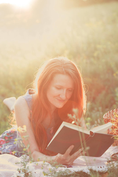 Summer - girl  reads a book  on a picnic in a meadow in the forest. - Foto, Bild