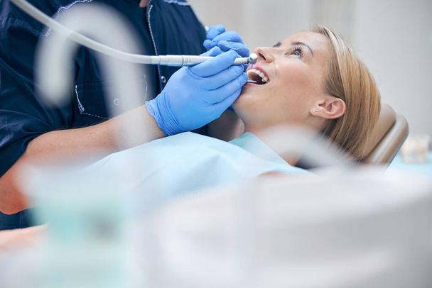 Dentysta traktuje młodą atrakcyjną kobietę z maszyną - Zdjęcie, obraz