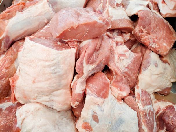 Vers rauw varkensvlees in koeltoonbank in supermarkt. Vers roze rauw varkensvlees in stukken gesneden door slager & verkopen bij vleesproduct in de supermarkt. Rauw varkensvlees heeft een hoog eiwitgehalte. Begrip varkensvlees. - Foto, afbeelding