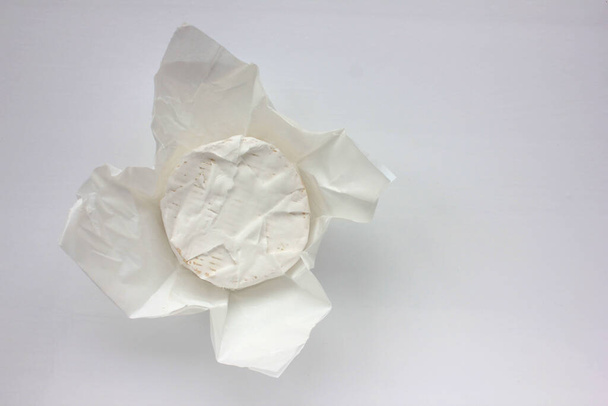 Camembert cheese on white packaging paper. Top view. Close up of white cheese - Foto, imagen