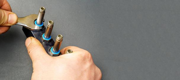 La mano de un hombre con una llave desatornilla el cilindro de gas del coche. Mantenimiento y reparación de equipos de gas para automóviles - Foto, Imagen