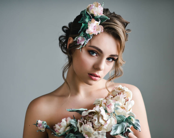 Beautiful woman with flowers in her hair. Beauty portrait of fashion model with creative makeup and hairstyle with a tender bouquet - Photo, Image