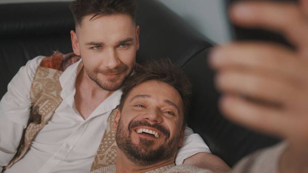 Funny romantic male gay couple using smartphone for video call. - 写真・画像