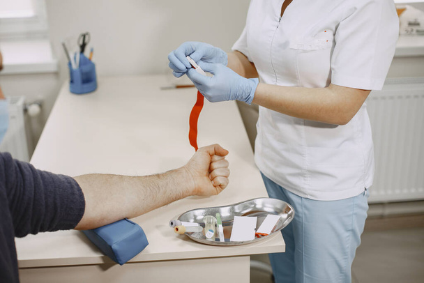 Pielęgniarka pobierająca krew od pacjenta z gabinetu lekarskiego - Zdjęcie, obraz