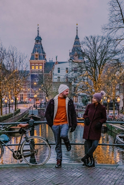 pár városnézés Amszterdam Hollandia csatornák karácsonyi fények decemberben, csatorna történelmi központjában Amszterdam éjjel - Fotó, kép