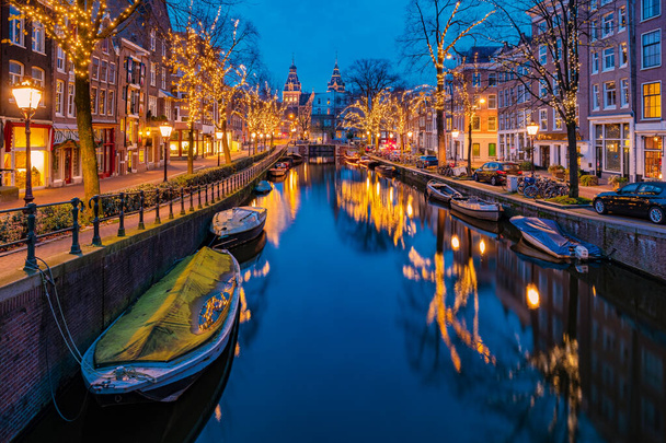 Amsterdam Países Bajos canales con luces de Navidad durante diciembre, canal centro histórico de Amsterdam por la noche - Foto, imagen